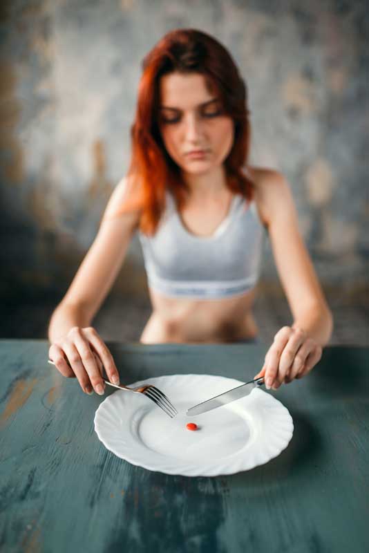 Woman against plate with a tablet for weight loss